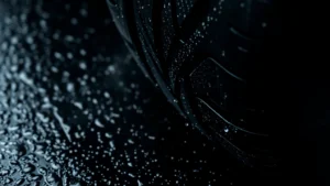 Close-up of high-performance tire tread pattern on wet asphalt surface, water droplets visible, dramatic lighting emphasizing grip and texture details